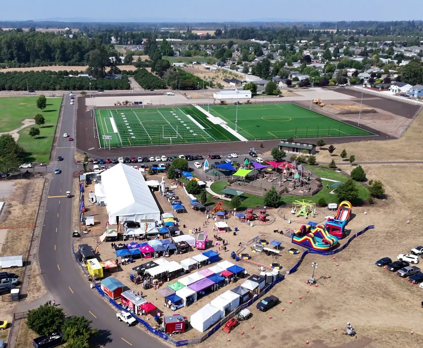 Aerial view of the KeizerFEST festival grounds with vendor tents and rides at Keizer Rapids Park